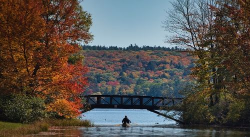 Une personne pagayant sur un lac entouré de couleurs automnales